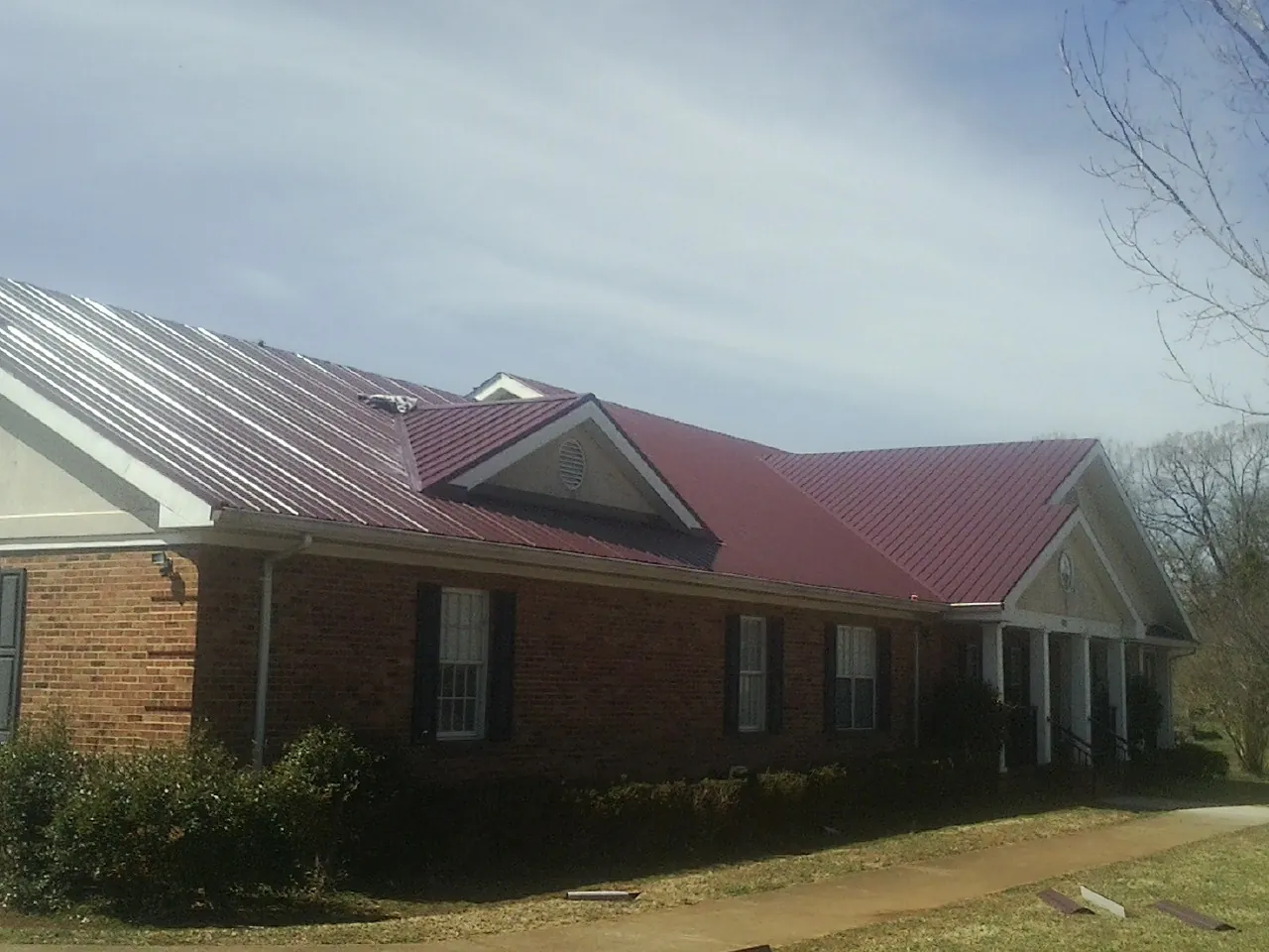 Red metal roof with gabled entries on a long brick building, from a Hail Damage Roof Repair job in Snowmass Village