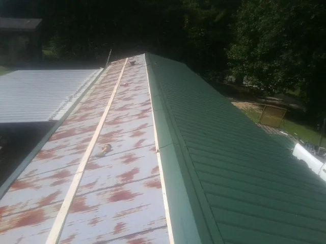 Old rusted panels beside newly installed green metal roofing — Wind Damage Roof Repair by Roofing Brothers in Snowmass Village
