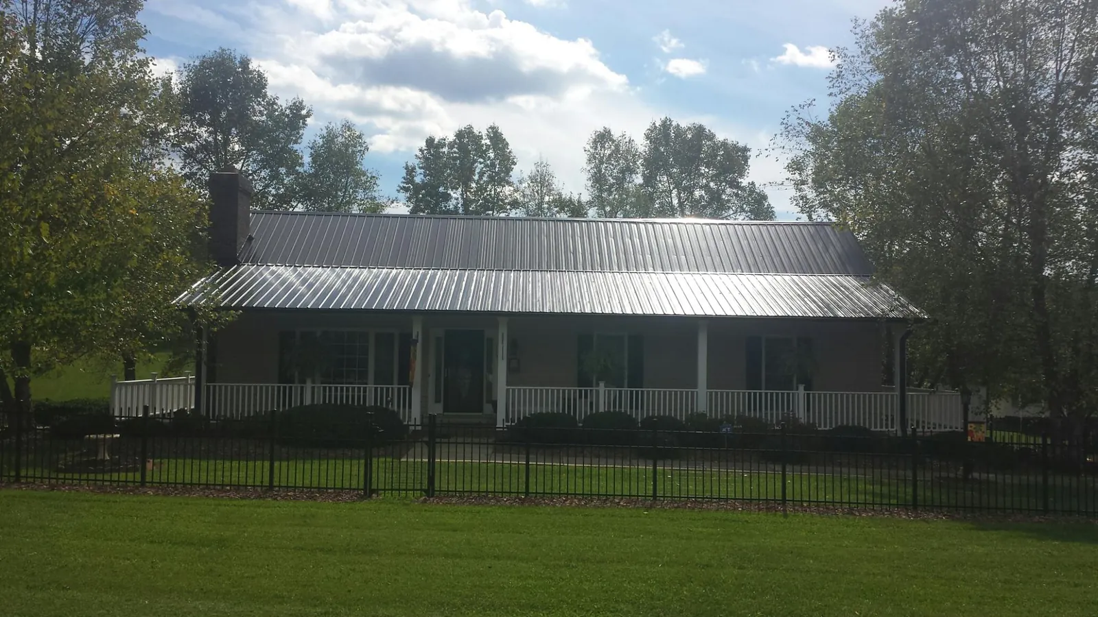 Gray metal roof on a brick ranch with a full width front porch — Gutter Guard Installation work by our crew in Snowmass Village