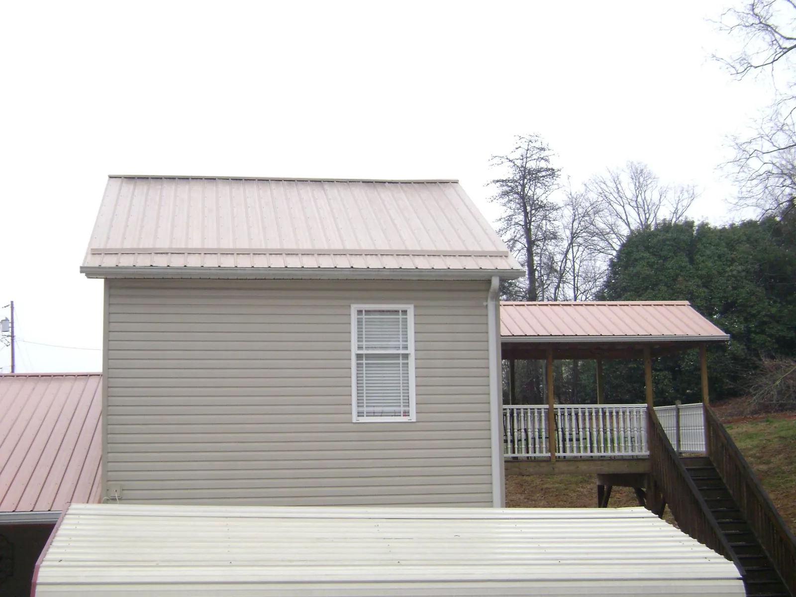 Tan metal roofs on a two story addition and attached porch, from a Roof Replacement job in Snowmass Village